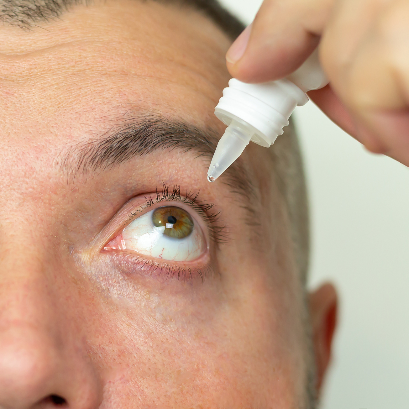 Man applying liquid eye drops in his eye solving vision problem close-up